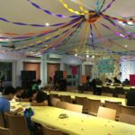 A room filled with party decorations and people busy with art drawings